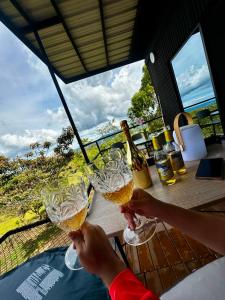 a person holding two glasses of beer at Tres Raices Cabañas in Gómez Plata
