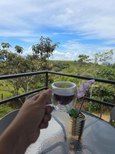a person holding a glass of wine on a table at Tres Raices Cabañas in Gómez Plata +24 photos