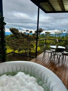 a hot tub on a deck with a table and chairs at Tres Raices Cabañas in Gómez Plata