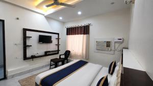 a bedroom with a bed and a mirror and a chair at The Grand Girivar Vrindavan # Lavis & Luxury Rooms # in Vrindāvan