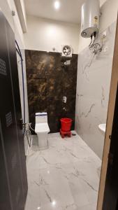 a bathroom with a toilet and a red bucket in it at The Grand Girivar Vrindavan # Lavis & Luxury Rooms # in Vrindāvan