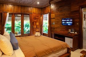 a bedroom with a bed with a television and windows at Pemedal Beach Resort in Nusa Lembongan