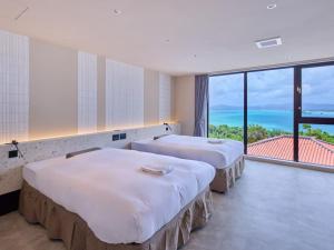 two beds in a room with a view of the ocean at Kandor Resort Okinawa in Nakijin +155 photos