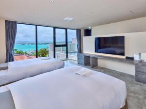 two beds in a hotel room with a tv at Kandor Resort Okinawa in Nakijin