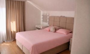 a bedroom with a pink bed with a stuffed animal on it at Vila Daško in Lukavac