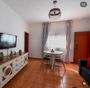a living room with a table and a tv at Villa balcón de azuaje in Moya