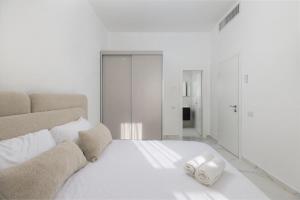 a white bed with two towels on top of it at Katalina Luxury Apartment Eilat in Eilat