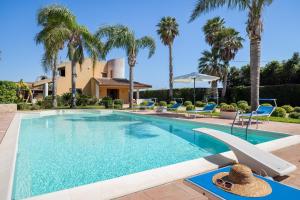 a swimming pool with palm trees and a house at Villa Tiffany in Marsala