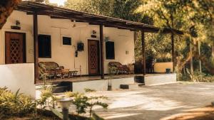 a house with a porch with chairs and trees at Vriksha Heritage Farm Stays in Sethumadai