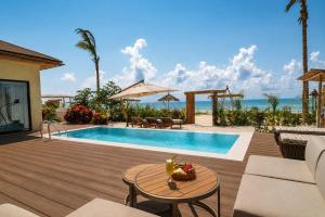 a backyard with a swimming pool with a table and chairs at ENVI Paje Wellness Lodge in Paje