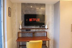 a television on a wall with a table and a yellow chair at Pillowtalks Cloudnine Stays in Ghaziabad
