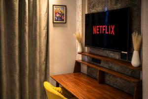 a living room with a tv and a curtain at Pillowtalks Cloudnine Stays in Ghaziabad +7 photos
