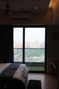a bedroom with a large window with a view of a city at Pillowtalks Cloudnine Stays in Ghaziabad