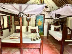 a bedroom with two beds and a canopy bed at Mustapha' s Place in Bwejuu