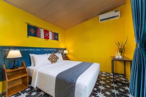 a bedroom with a bed and a yellow wall at Catba Papillon Garden Bungalows & Resort in Cat Ba
