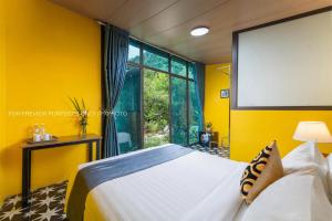 a yellow bedroom with a bed and a large window at Catba Papillon Garden Bungalows & Resort in Cat Ba
