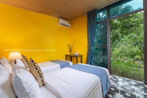 two beds in a room with a large window at Catba Papillon Garden Bungalows & Resort in Cat Ba