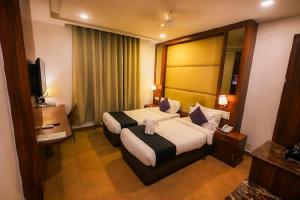 ein Hotelzimmer mit einem großen Bett und einem Fernseher in der Unterkunft Dazzling A Boutique Hotel in Agra + 66 Fotos