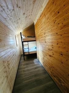 a small room with a bed in a wooden wall at Căsuța Elena Refugiu în Natură in Buceş