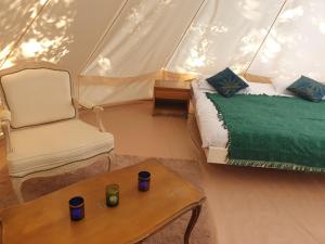 a room with a bed and a chair in a tent at Domaine du Fourtet in Arfons