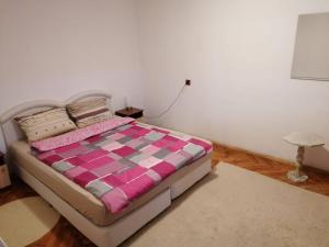 a bedroom with a bed with a pink and purple comforter at Shumata Guest House in Natsovtsi +2 photos
