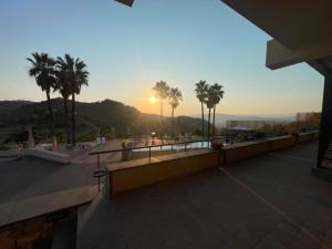 Ein Balkon mit Palmen und dem Sonnenuntergang im Hintergrund in der Unterkunft Kento Resort in Centuripe