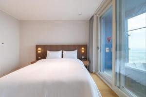 a bedroom with a large bed and a large window at 플럼바고올스위트1407 in Chosan-ni