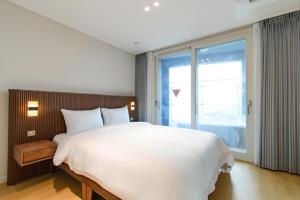 a bedroom with a large bed and a large window at 플럼바고올스위트1407 in Chosan-ni