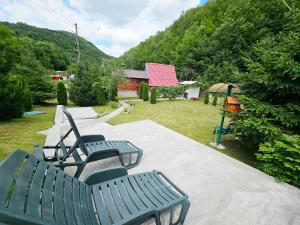 a group of green benches sitting in a yard at Căsuța Elena Refugiu în Natură in Buceş