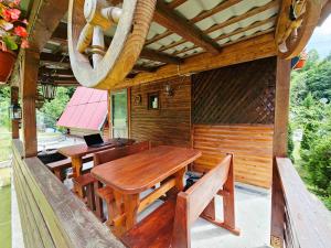 a wooden porch with a wooden table and benches at Căsuța Elena Refugiu în Natură in Buceş
