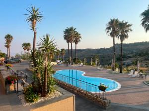 ein Schwimmbad auf einem Parkplatz mit Palmen in der Unterkunft Kento Resort in Centuripe