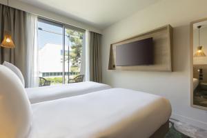 a hotel room with two beds and a tv at MERCURE NIMES CENTRE ARENES in Nîmes