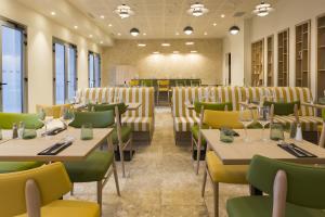 a dining room with tables and chairs and windows at MERCURE NIMES CENTRE ARENES in Nîmes +41 photos