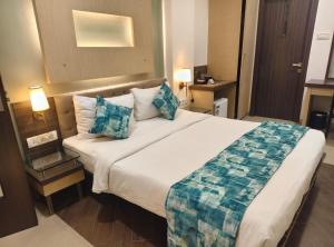 a hotel room with a large bed with blue pillows at Hotel Mumbai House Thane in Thane