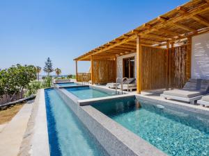 an infinity pool with a villa in the background at Paradise Beach Resort in Paradise Beach