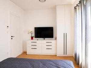 a white bedroom with a television on a white dresser at Royal Rest Apartments Karlovac-Luxury, Central Location & Free Parking in Karlovac