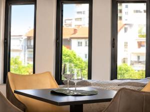 a table with wine glasses and chairs in front of a window at Royal Rest Apartments Karlovac-Luxury, Central Location & Free Parking in Karlovac