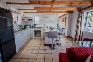 a kitchen with white cabinets and a tile floor at Serenity Cottage in Swellendam