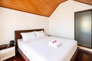 a bedroom with a white bed with two red balls on it at Royal Indah Glamping Kintamani in Kintamani