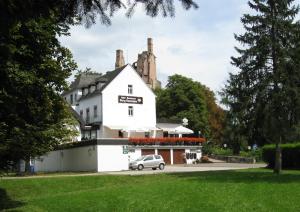 un edificio blanco con un coche aparcado delante de él en Hotel-Restaurant Burg-Ramstein en Kordel