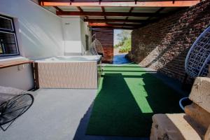 an internal courtyard with a green floor and a brick wall at Serenity Cottage in Swellendam