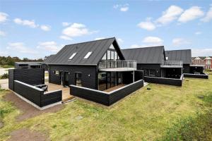 a large black house on a grass field at 0431-Romo-Vestergade-333 in Høm