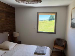 a bedroom with a bed and a window and a chair at Le Chalet du Soleil Levant in Longevilles-Mont-dʼOr