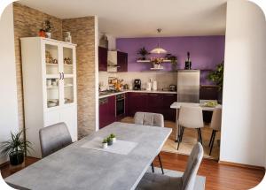 a kitchen with purple walls and a table and chairs at Beautiful duplex apartment with view in Kaštela