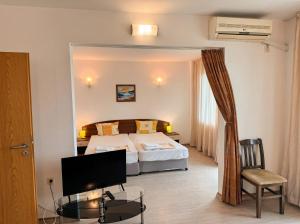 a hotel room with a bed and a desk with a tv at Семеен Хотел Примо Family Hotel Primo in Primorsko +34 photos