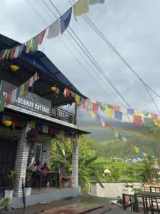 Eine Gruppe von Menschen sitzt an einem Tisch auf einem Gebäude mit Flaggen. in der Unterkunft Hideaway Cottage in Pokhara