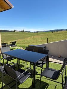 a table and chairs on a patio with a field at Le Chalet du Soleil Levant in Longevilles-Mont-dʼOr