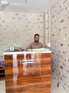 a man is sitting at a reception desk at Rajratna lodge in Lohogaon