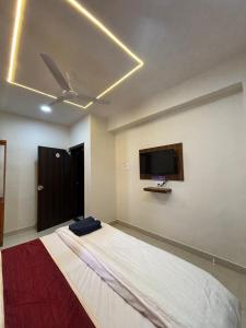 a bedroom with a bed with a ceiling fan and a tv at Rajratna lodge in Lohogaon
