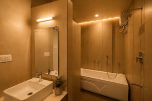 a bathroom with a sink and a tub and a mirror at Ayana Lake Resorts in Kovillūr +23 photos